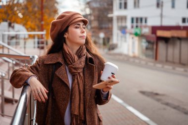 Kafkasyalı genç bir kadının kenarda bir fincan kahveyle dolaşması. Özgürlük ve şehir yaşam tarzı kavramı.