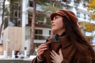 Sonbahar ışığı ve boş sokakların portresi genç bir kadının düşünceli bir şehir yürüyüşü için huzurlu bir zemin oluşturur.