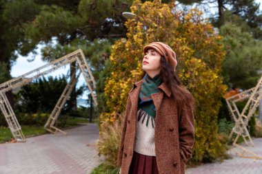 Huzurlu sonbahar sokakları, hafta sonu kaçamağından zevk alan düşünceli bir kadının yalnız yürüyüşünü hoş karşılıyor.