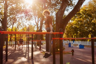 Yatay spor barından orta boy kızıl saçlı kadın şınavı. Spor anlayışı ve açık hava eğitimi.