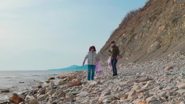 İki kadın çevreci kumsaldan atık toplamak, kirlilikle mücadeleye ve deniz yaban hayatını korumaya yardım etmek için birlikte çalışıyor. İnsanlar Dünya Günü koruma çabalarına katılıyorlar. Geniş açı.