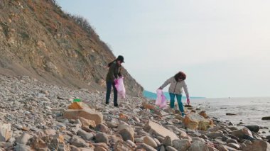 Gönüllüler kirliliği önlemek için okyanus kıyısından plastik şişe, torba ve diğer enkazı kaldırıyorlar. İnsanlar doğal çevreyi yeniden inşa etmek ve vahşi yaşamı korumak için harekete geçiyor. Geniş açı.