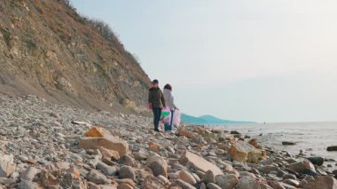 Gönüllüler kirli bir plajı temizlemek, plastik atık toplamak ve çevresel yıkımı önlemek için birlikte çalışıyorlar. İnsanlar doğayı koruma çabalarına katılıyorlar. Geniş açı.