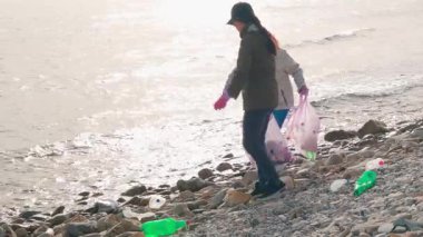 İki kadın eylemci plajdan plastik ve diğer çöpleri topluyor, okyanus kirliliğini önlüyor ve çevresel sorumlulukla ilgili farkındalığı artırıyor. Koruma kavramı
