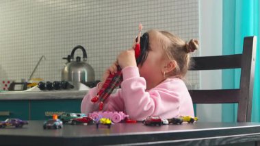 Beyaz çocuğun orta pozu oyuncaklara ve eğlenceli bir öğrenme alanındaki bir masadaki eğitici oyuncaklara odaklanıyor. Etkinliklerdeki eller motor koordinasyonu, yaratıcılığı ve erken kavramsal becerileri geliştirir.