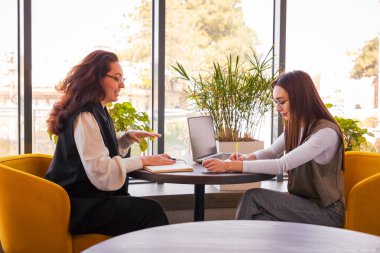 Kendine güvenen beyaz kadınlar öğle yemeğinde şık bir kafede yeni pazarlama çözümleri, dijital ekonomi konsepti ve çevrimiçi iş dünyasında takım çalışmasını tartışıyor. Yan görünüm.