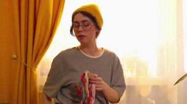 Bir yatakta oturan beyaz bir kadının orta pozu ve halka ile nakış çalışması. Yaratıcı eğlence zamanı ve ev içi dekorasyonda sakinleştirici hobi