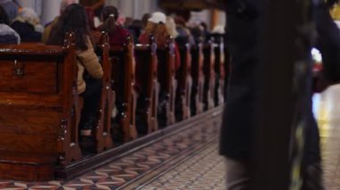 Noel 'de bir Katolik cemaatinin ikonlar, mevsimlik dekorasyonlar ve bir doğum sahnesiyle arka planda kalan görüntüsü.