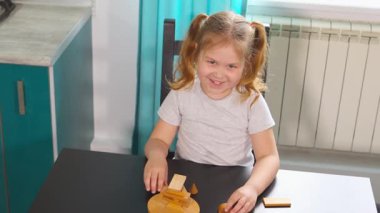 Küçük beyaz çocuk anaokulu sınıfındaki bir masada eğitici blok oyunları oynuyor. Yapı kalıpları hayal gücünü teşvik eder ve erken öğrenme kavramlarını güçlendirir. Orta çekim.