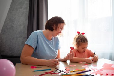 Kafkasyalı genç bir kadın ve küçük tatlı bir kız bir masada birlikte resim yapıyorlar. Okul öncesi çocukların eğitimi..