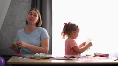 Kafkasyalı küçük bir kızın Anneler Günü 'nde annesine kartpostal attığı bir fotoğraf. Aile masaya oturur ve el işi yapar..