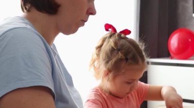 Genç bir kadın ve gülümseyen beyaz bir kız kağıt sevgililer günü kartı süsler. Düşük açı. Sevgililer Günü ve Anneler Günü Kutlamaları.