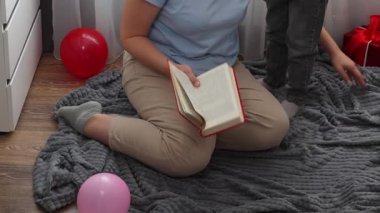 Anne ve beyaz bir kız birlikte masal kitabı okuyorlar. Üst Manzara. Anneler Günü ve anaokulu eğitimi kavramı.