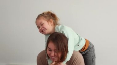 Mutlu bir anne ve küçük beyaz bir kızın yatakta birlikte oynadığı orta resim. Mutlu aile zamanları. Alt görünüm.