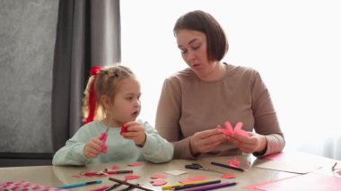 Kafkasyalı genç bir kadının portresi ve şirin küçük bir kız birlikte bir masada oturup bayram için el sanatları yapıyorlar. Okul öncesi çocukların eğitimi..