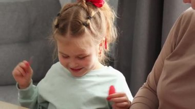 Küçük, mutlu, beyaz bir kızın elinde kağıttan bir kalp ile kalp atışını gösteriyor. Anneler Günü ve Sevgililer Günü konsepti.