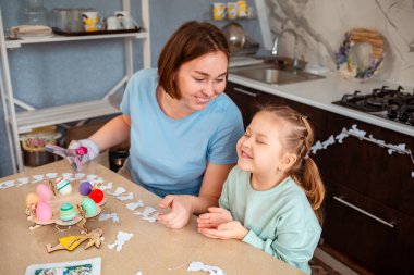 Annesiyle kızının Paskalya masasında oturup oyun oynadığı bir kare. Üst Manzara. Mutlu aile tatilleri..