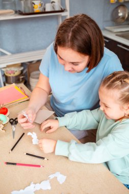 Genç ve güzel bir anne ve küçük tatlı bir kızın Paskalya bahar tatili için el sanatları çalışmalarının en güzel manzarası. Dikey.
