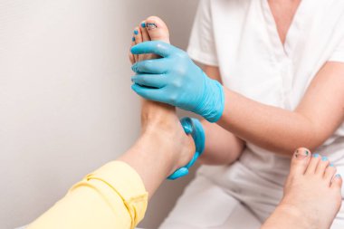 Bir ayak bakım uzmanı müşterinin ayağına masaj yapar. Bacakları ve ayak tırnakları titanyum iplikle yakın plan. Pedikür ve podoloji kavramı.