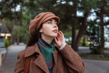 Zarif genç bir kadının portresi, sakin şehirde hafta sonu havası ve mevsimsel güzelliğin tadını çıkararak, ılık giysiler içinde yavaşça dolaşır..