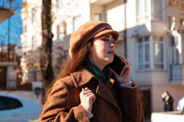Beyaz bir kadının portresi, paltosu ve beresi olan, sokakta akıllı bir telefondan arayan. Şehir yaşam tarzı.