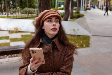 Rahat katmanlar içinde güzel bir kadın rengarenk sokaklarda yürürken akıllı telefonunu karıştırıyor ve hafta sonları şehir hayatının tadını çıkarıyor.