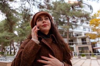 Zarif giyimli genç kadın portresi sakin şehir sokaklarında yürürken izin günlerinde telefonla bağlanıyor.