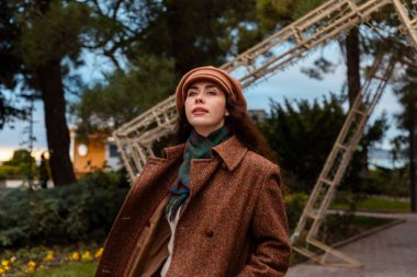 Paltolu genç bir kadın şehri tek başına keşfediyor, sakin duygular ve zihinsel odaklanma ifade ediyor.