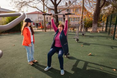 Olgun bir beyaz kadın, tedavi sonrası kişisel antrenörüyle birlikte rehberli bir egzersiz programına uyar. Rehabilitasyon ve aktif yaşam tarzı gücün ve bağımsızlığın geri gelmesine yardımcı olur