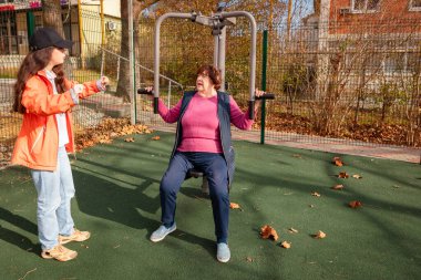 Yaşlı beyaz kadın, ameliyattan sonra iyileşme sürecinin bir parçası olarak parkta spor yapıyor. Egzersiz gücü, dengeyi ve uzun vadeli sağlığı geliştirir.