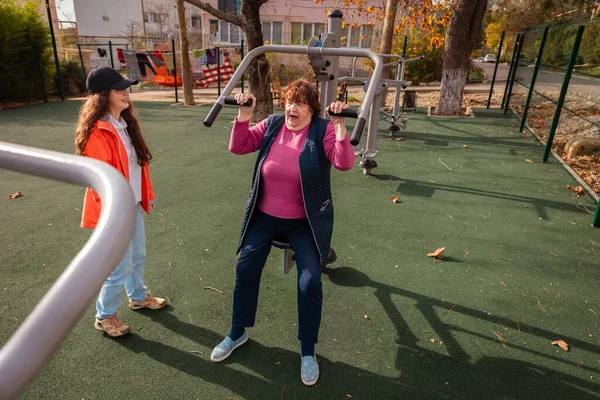 Yaşlı kadın, hastalık sonrası iyileşme sürecinin bir parçası olarak antrenör gözetiminde egzersiz yapıyor. Yapılandırılmış spor rutini önleme ve sağlıklı yaşlanmayı destekler