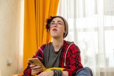 Beyaz kadın gencin evde boş vakit geçirmekten hoşlandığı portresi. O, yatakta otururken televizyon izler. Ev rahatlığı fikri