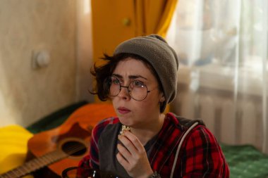 Kafkasyalı genç kız öğrencinin portresi evde televizyonla rahatlıyor. Yatağa rahatça oturur ve patlamış mısır yer. Ev eğlencesi fikri