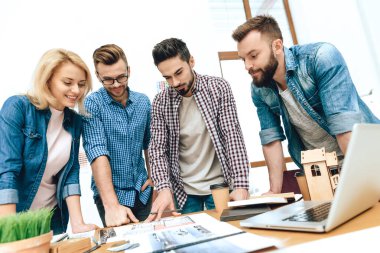 Genç tasarımcılar bir çarşafa bakıyor..