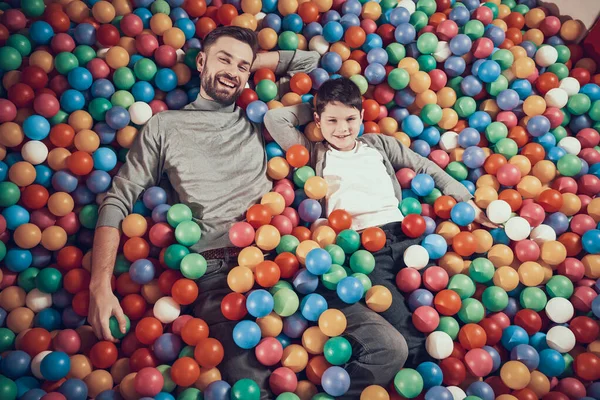 Papá e hijo miran a la cámara mientras están acostados en bolas. —  Fotos de Stock