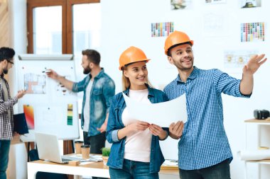 İki tasarımcı kağıtlarla poz veriyor..