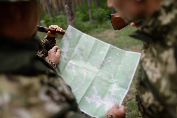 Hunters Holding Topographical Map Planning Route.