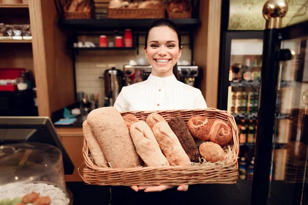 Jonge lachende vrouw staand met brood in de bakkerij. — Stockfoto