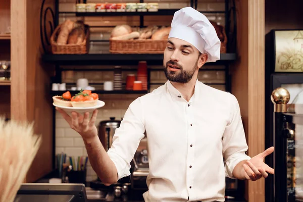 Jonge baard man met taart staande in de bakkerij. — Stockfoto