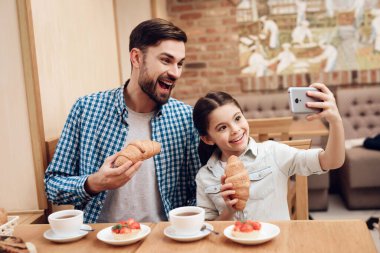 Baba ve kızı kafeteryada selfie çekiyorlar..