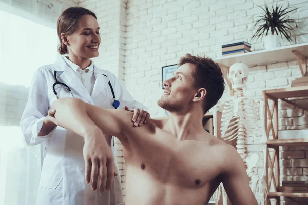 Een man met een naakte romp kijkt naar een vrouwelijke dokter. — Stockfoto