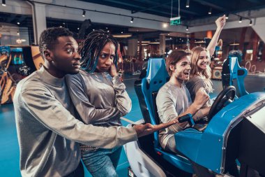 İnsanlar sanal yarış oynayan bir çifti izliyorlar.