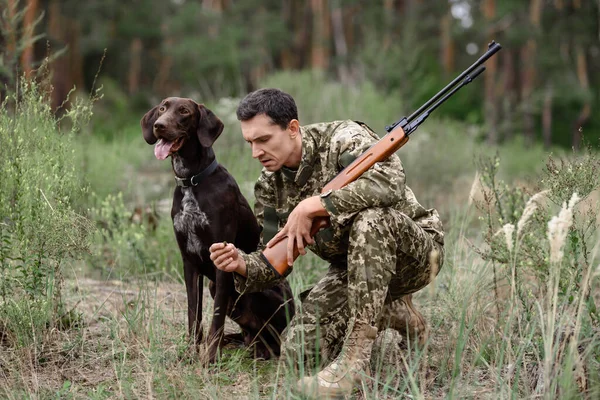 Hunter ocupa en verano bosque caza perro se sienta. — Foto de Stock