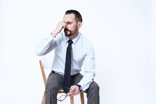 Un hombre se sienta en una silla y siente dolor en su cabeza. — Foto de Stock