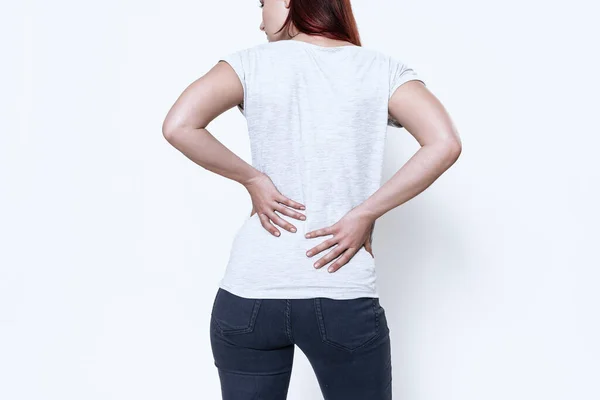 Girl turned back to camera and hold a sore back. — Stock Photo, Image