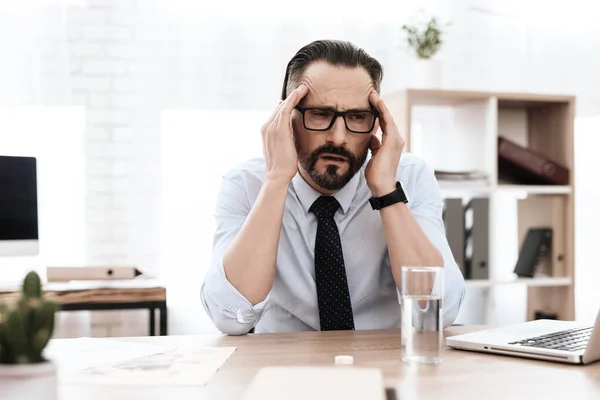 Un hombre con barba en su escritorio siente migraña.. — Foto de Stock