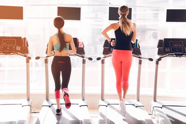 Las niñas corren juntas en el gimnasio en las cintas de correr. — Foto de Stock