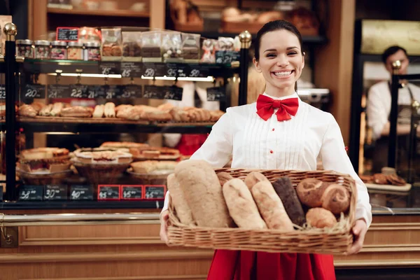 Jonge bakker staat in een bakkerij met vers brood. — Stockfoto