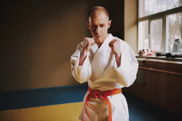 Man stands in a karate stand and looks at camera.