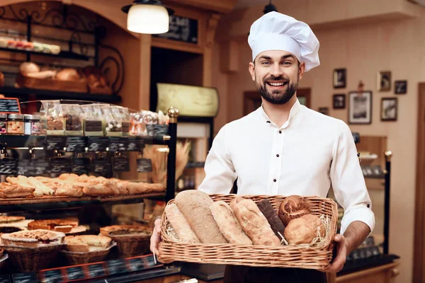 Jonge man met baard in witte pet staand in de bakkerij. — Stockfoto